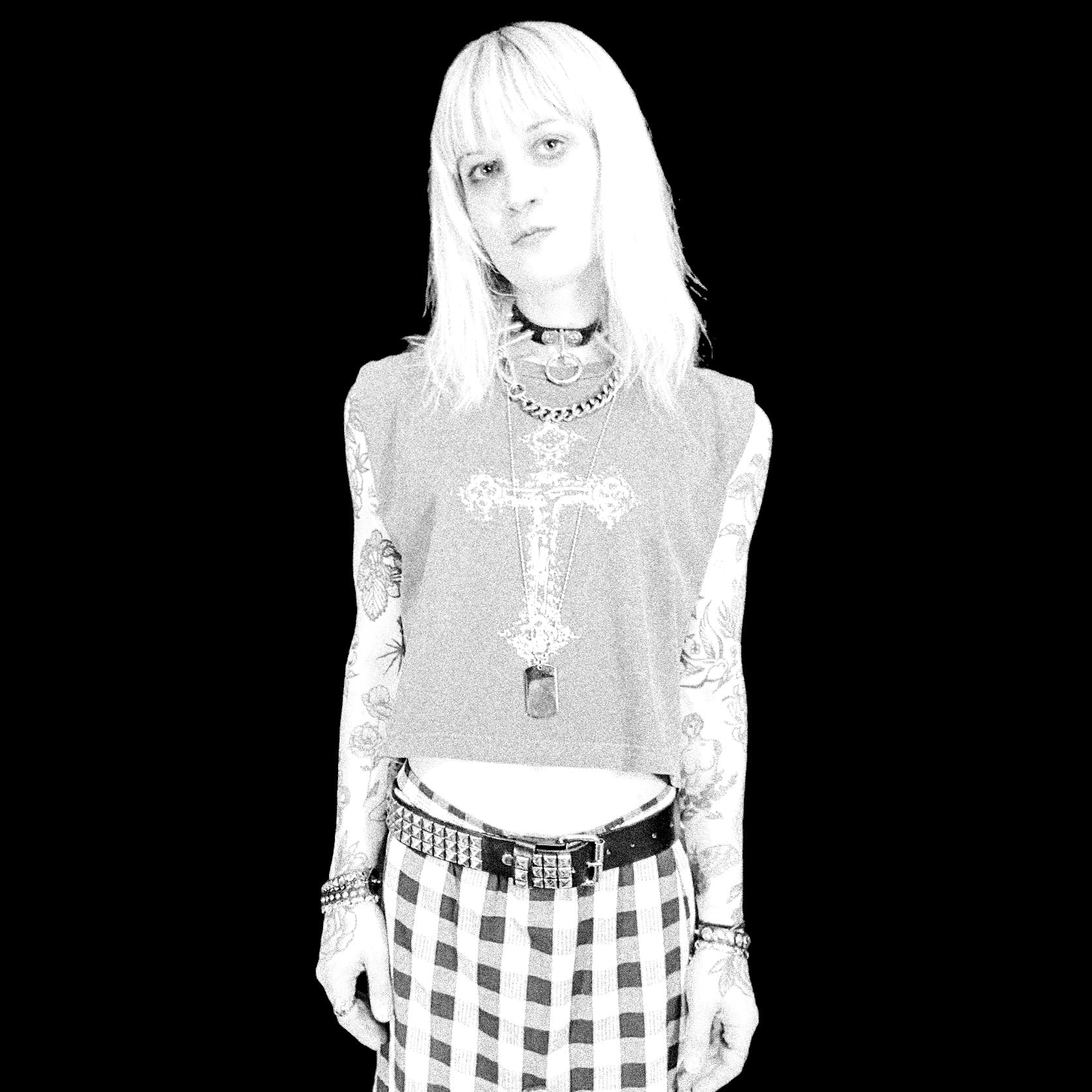 Black and white photo of a person wearing a detailed top and checkered skirt.