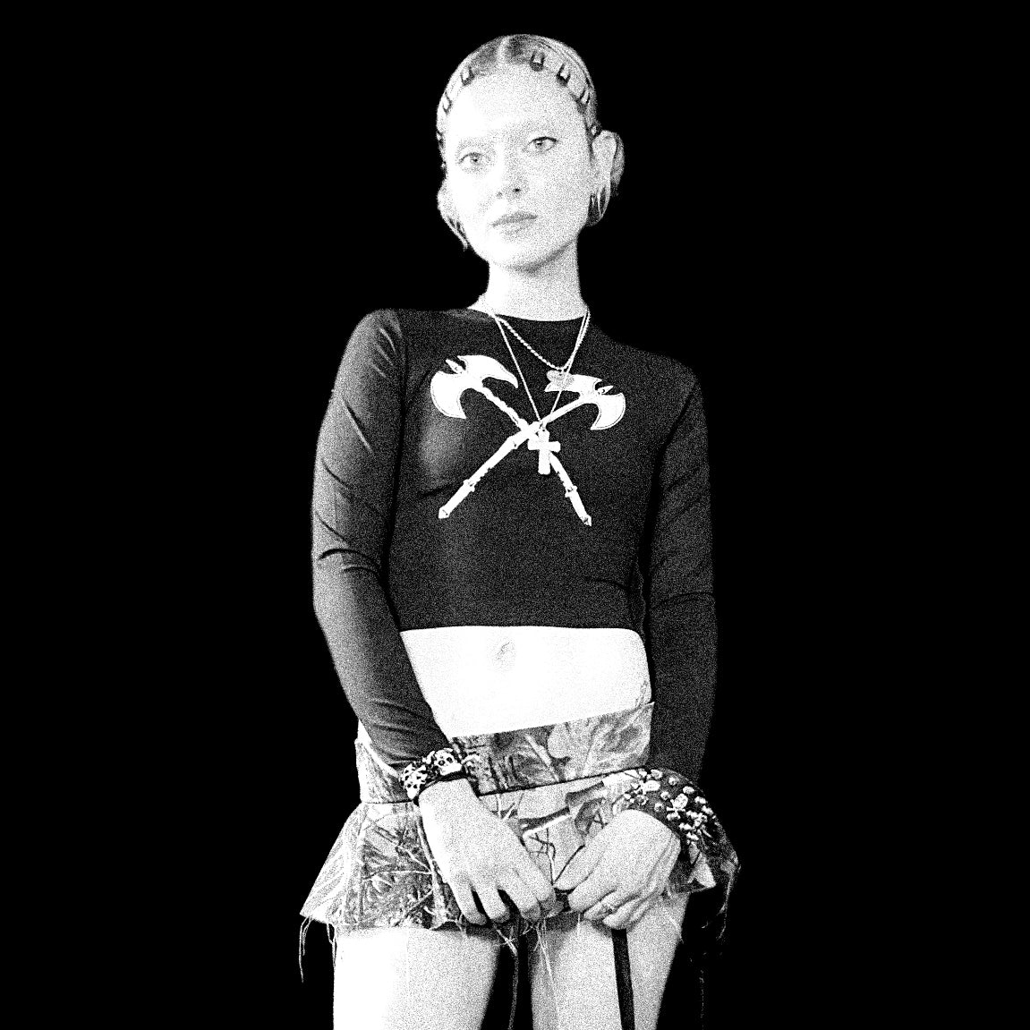 Black and white photo of a person wearing a sweater with crossed axes design.