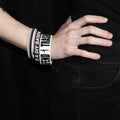 Person wearing a bracelet with text on a black background