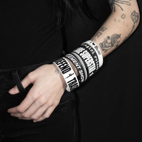 Person wearing multiple bracelets with text on a black background