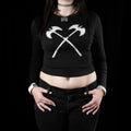 Person wearing a black long-sleeve shirt with crossed axes design on a black background