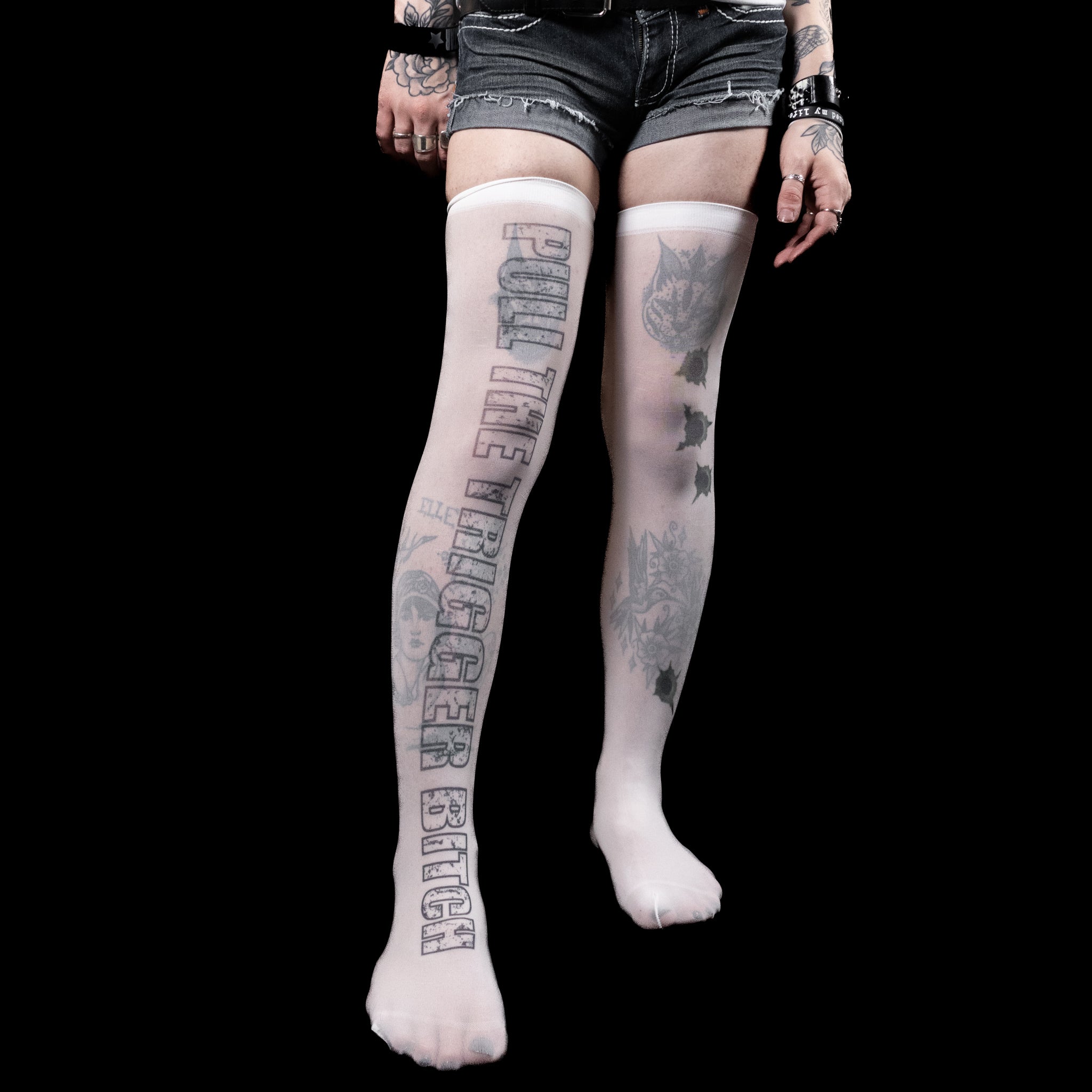 Person wearing thigh-high socks with text and tattoos on a black background