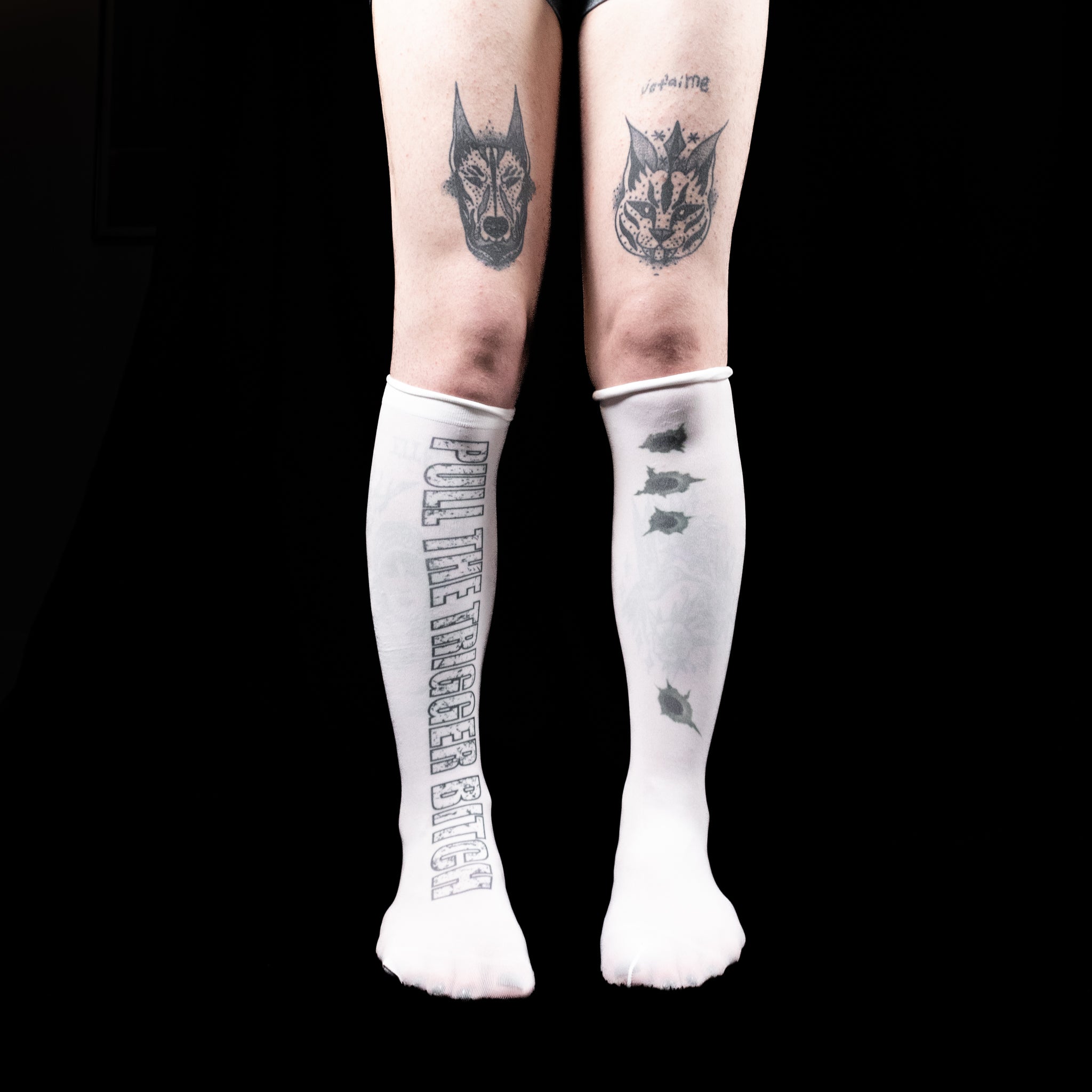 White knee-high socks with printed text and graphics worn by a person on a black background