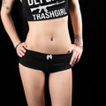 Person wearing a black crop top with text and black shorts on a black background