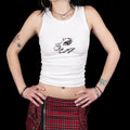 Person wearing a white tank top with a graphic design and a red plaid skirt on a black background