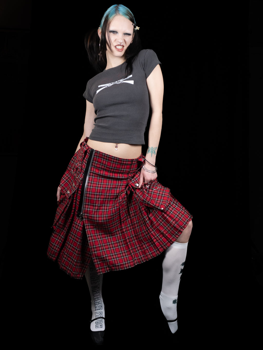 Person wearing a black crop top and red plaid skirt on a black background