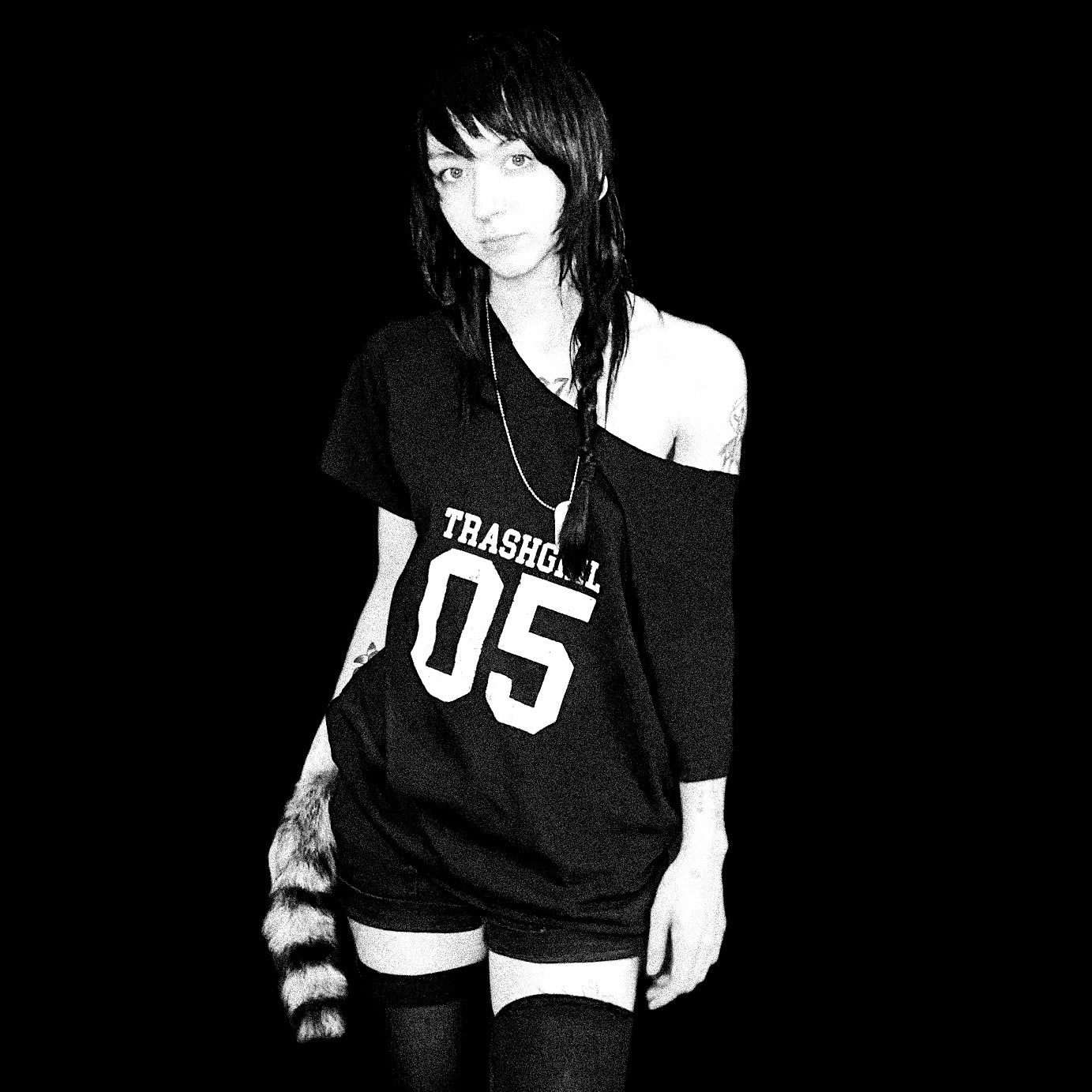 Black and white photo of a person wearing a 'TRASHGIRL' oversized t-shirt with '05' printed on it.