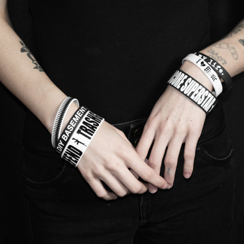Close-up of hands wearing multiple bracelets with text on a black background