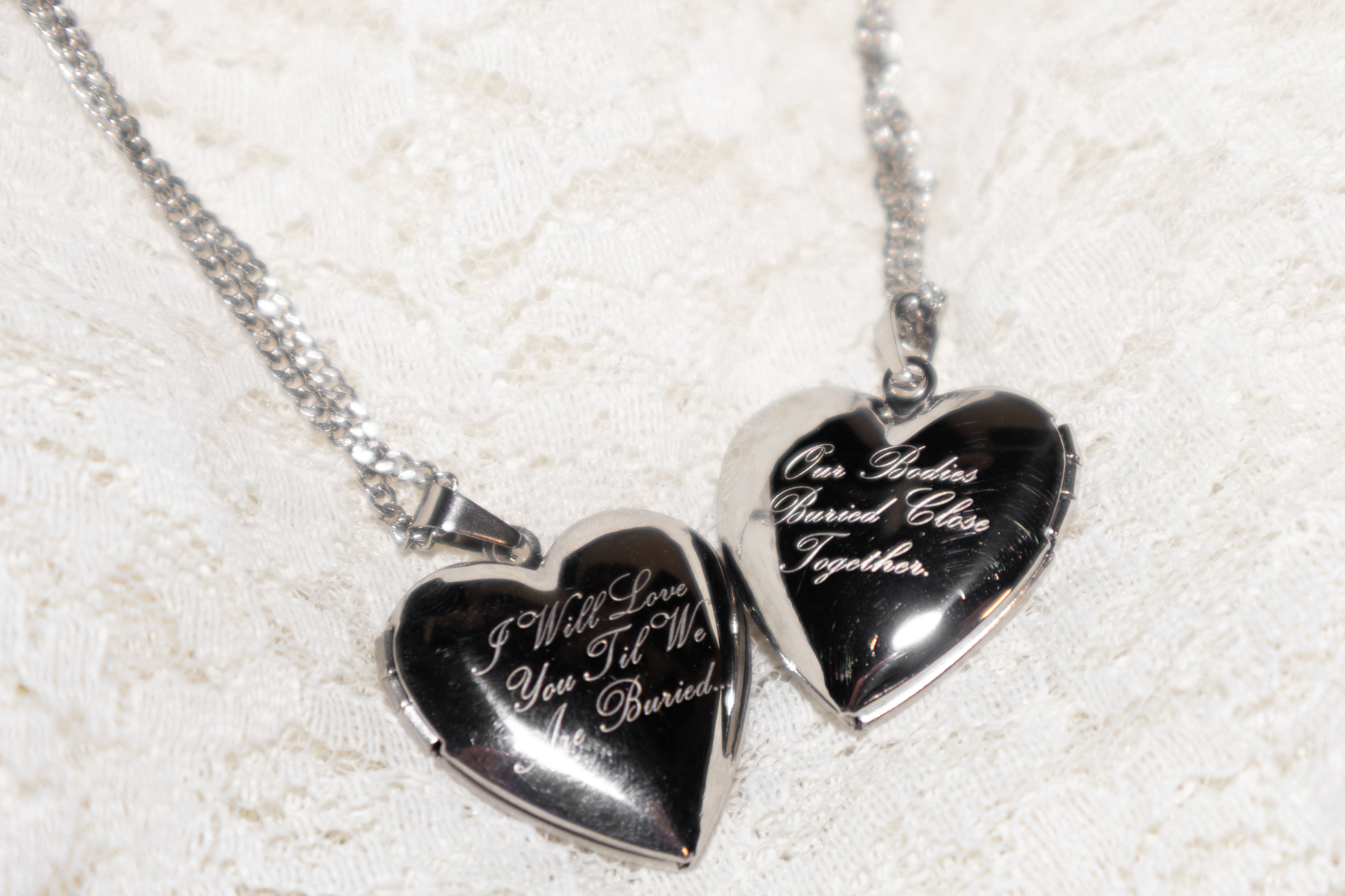 Heart-shaped silver pendants with engraved text on a textured white background