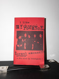 A red fan zine titled 'i like my chemical romance. a normal amount!!!' by trashgirl! standing upright on a black surface against a white wall.